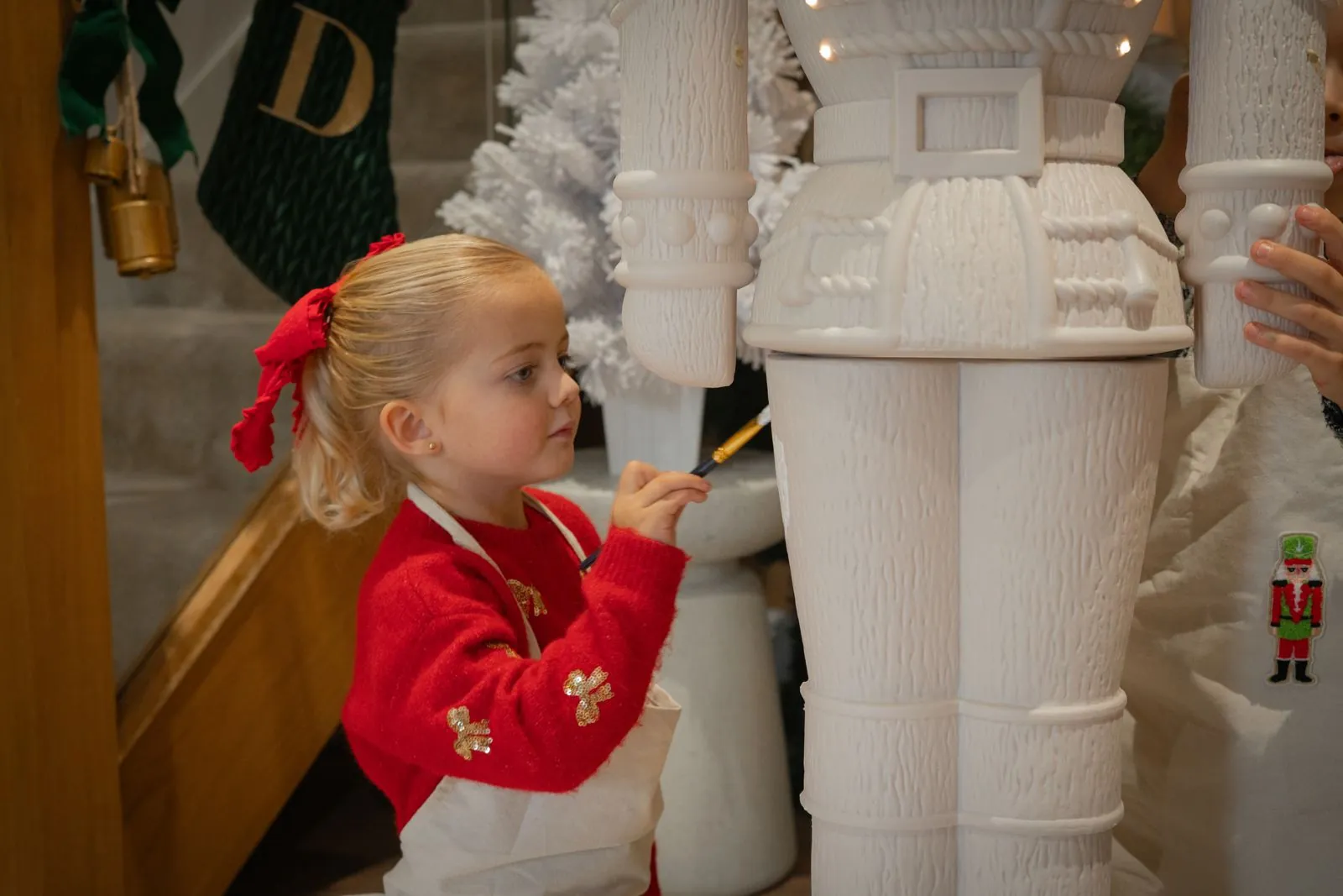 A child in an apron carefully painting a Paint Your Own Otto